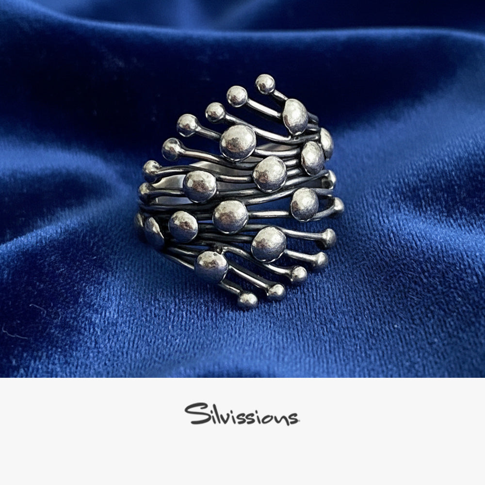 Silver ring with a unique design on a blue fabric background