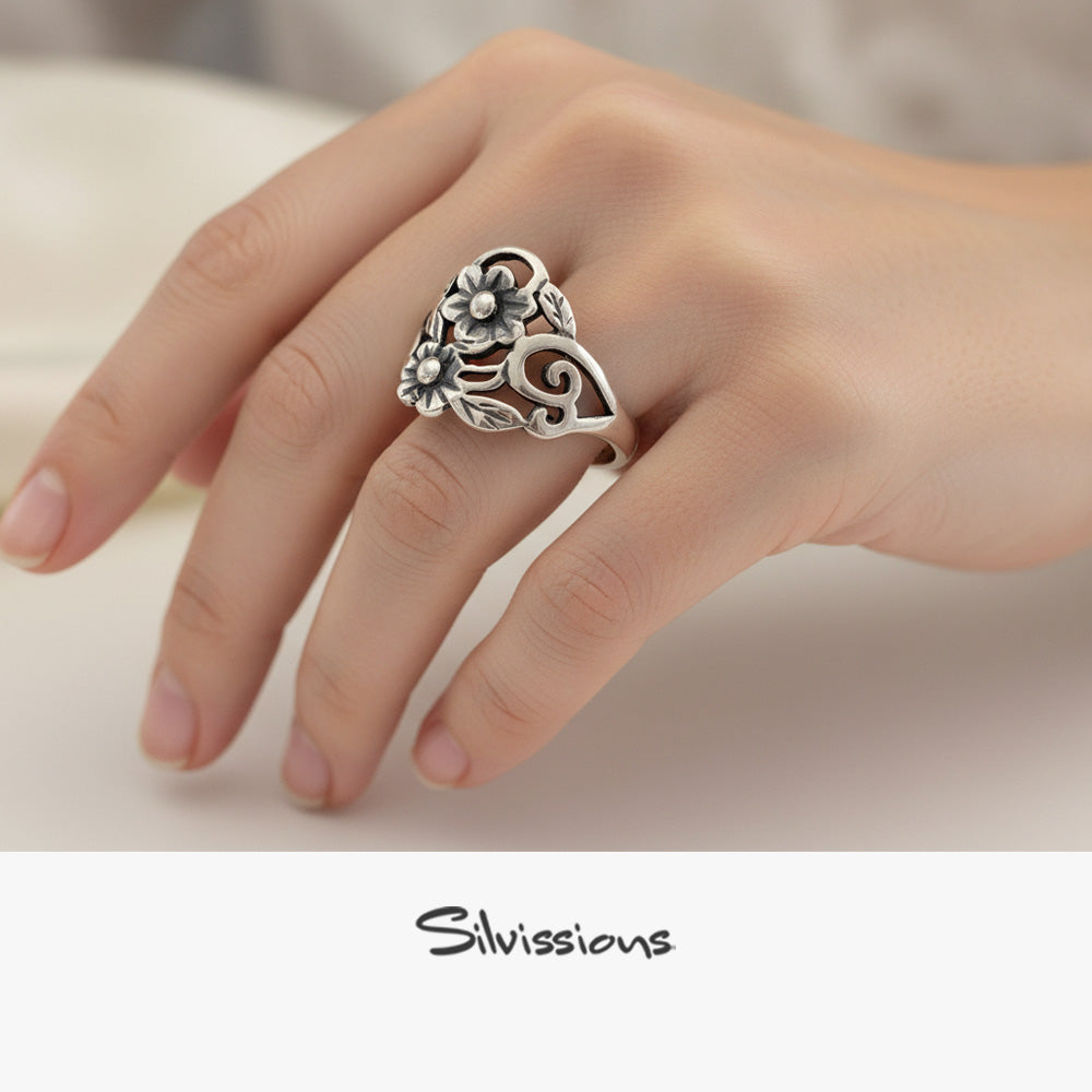 Silver floral ring on a person's finger with 'Silvissions' branding.