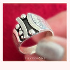 Silver ring  held by a hand against a red background, featuring the brand 'Silvissions'.