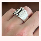 Silver ring with textured band worn on a finger, brand 'Silvissions' visible