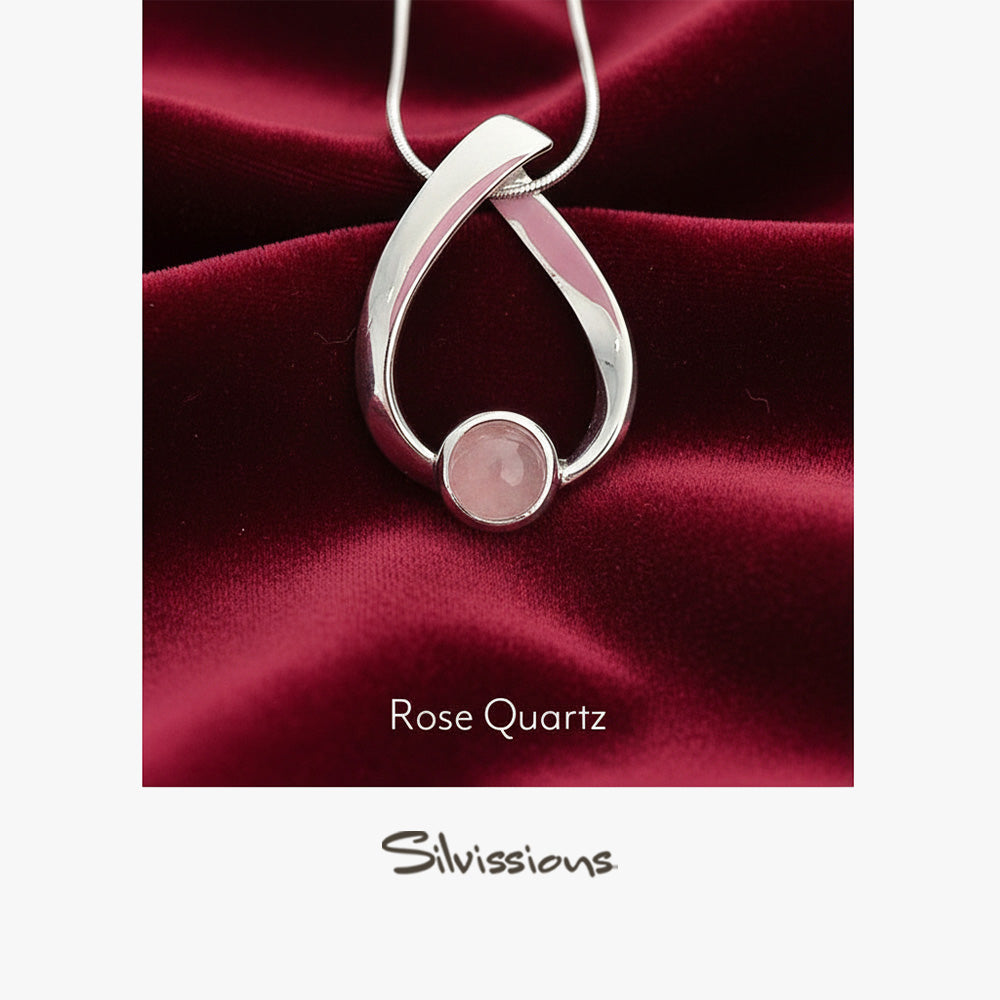 Silver pendant with rose quartz stone on red satin background, featuring 'Silviussions' brand.