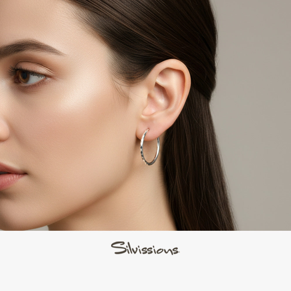 Close-up of a woman wearing a silver hoop earring with 'Silvassions' branding.