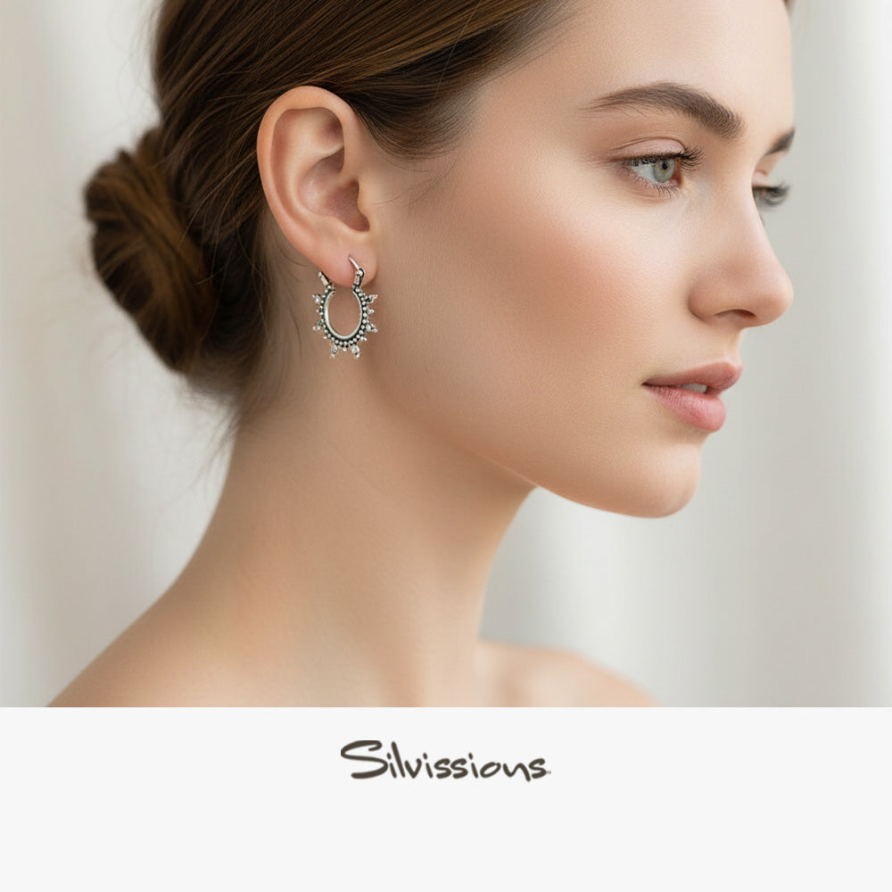 Close-up of a woman wearing a silver hoop earring with 'Silvissions' branding.