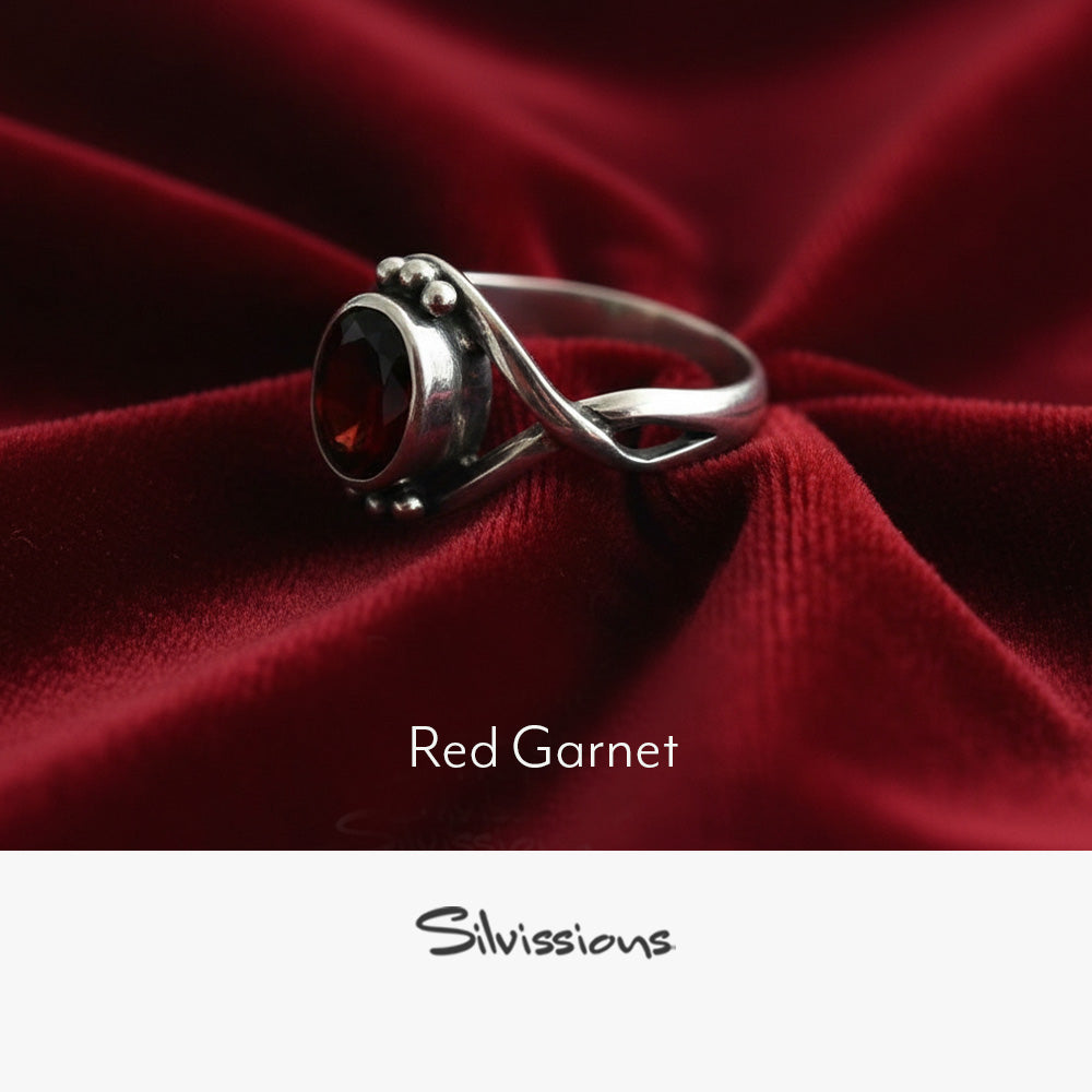 Silver ring with red gemstone on red fabric, branded 'Silvissions'.