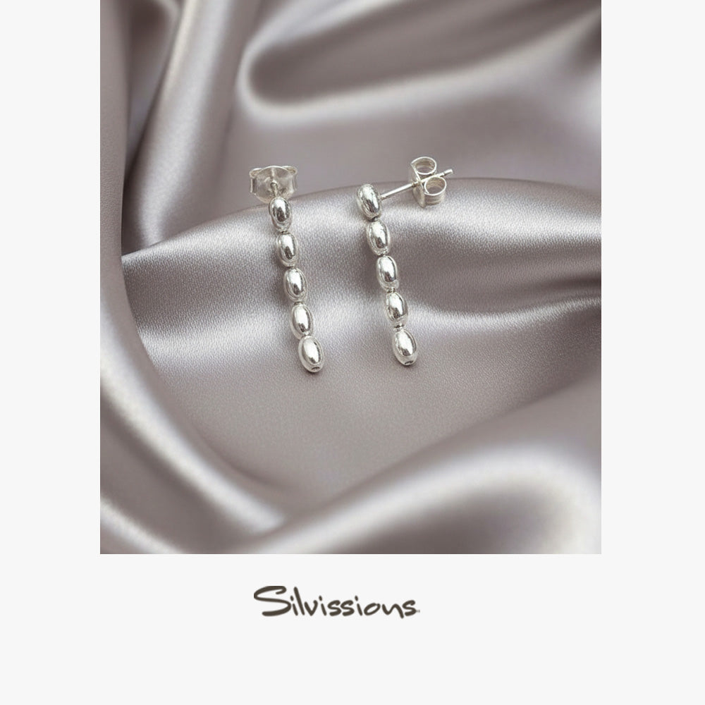 Silver earrings on a satin fabric background