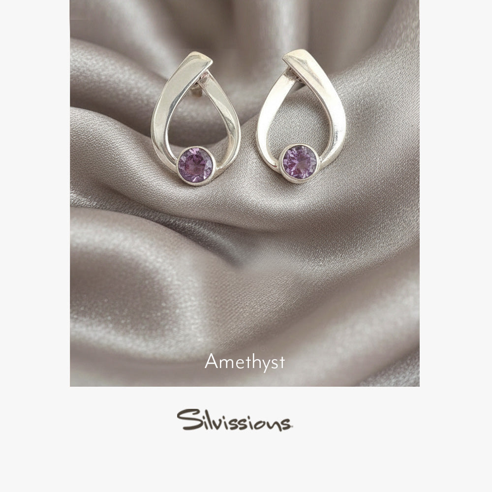 Silver earrings with amethyst gemstones on a silverfabric background, featuring the Silvissions brand.