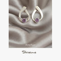 Silver earrings with amethyst gemstones on a silverfabric background, featuring the Silvissions brand.