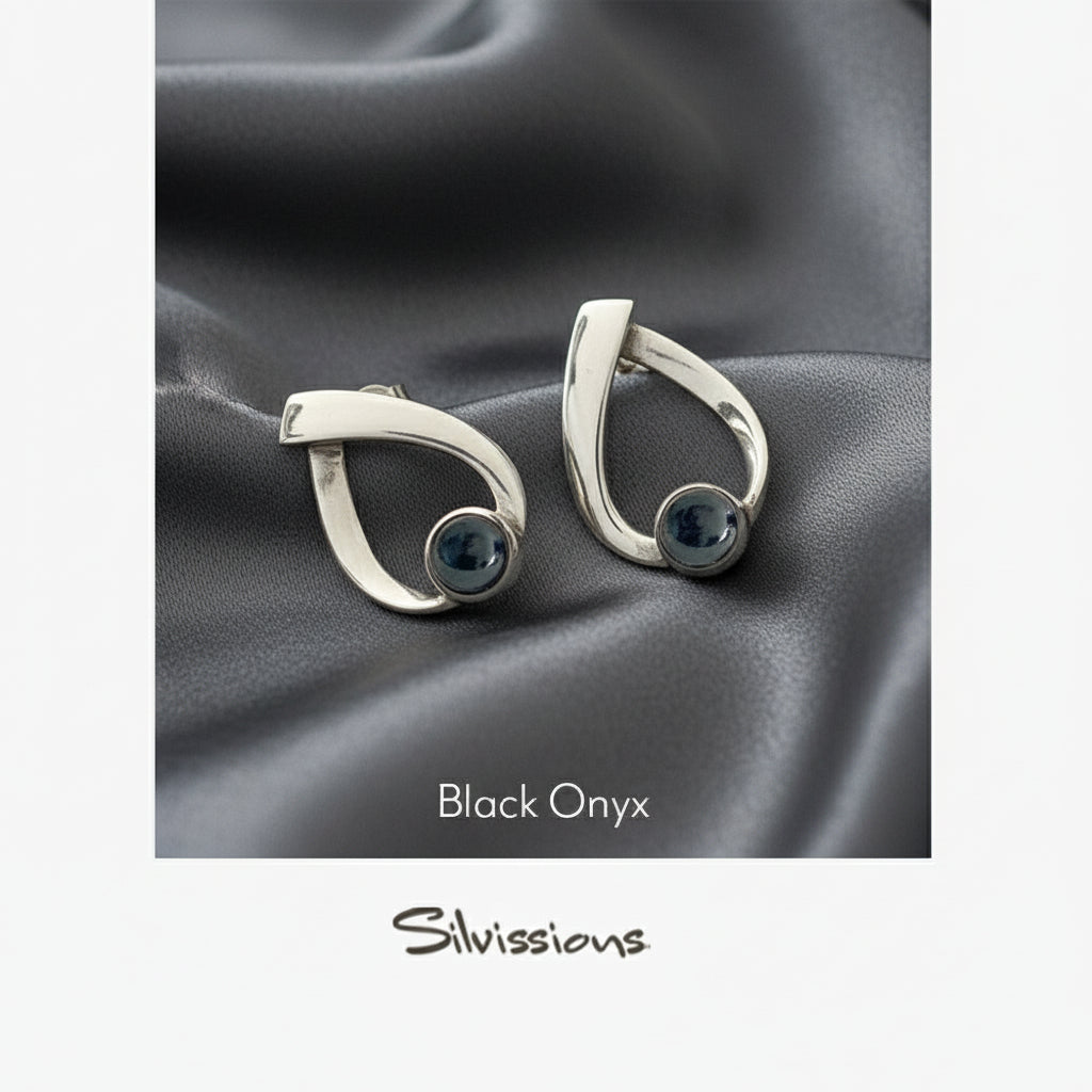 Pair of silver earrings with black onyx stones on a gray fabric background, featuring the brand 'Silvissions'.
