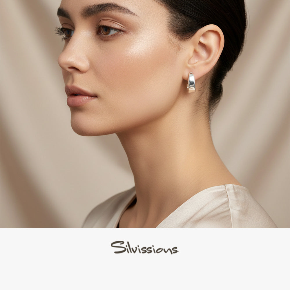 Close-up of a woman wearing silver stud earrings with 'Silvissions' branding.
