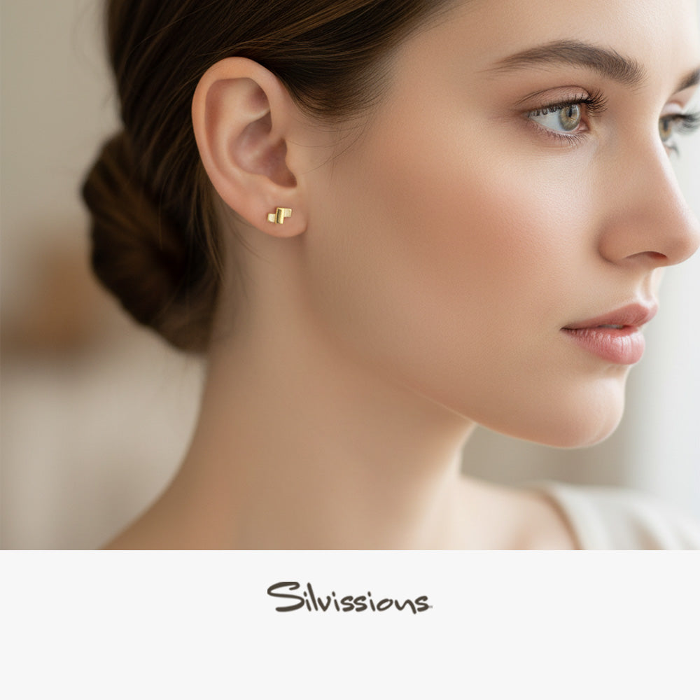 Close-up of a woman wearing mixed metal stud earrings with 'Silvassions' branding.
