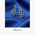 Silver feather-shaped earrings on a soft blue fabric background with 'Silvissions' branding.