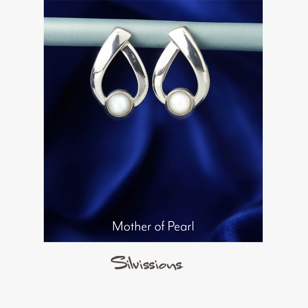 Pair of silver earrings with mother of pearl stones on a blue satin background, branded 'Silvissions'.