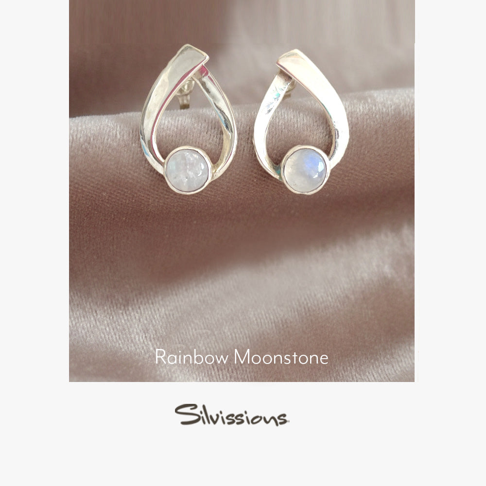 Silver earrings with rainbow moonstone gemstones on a soft fabric background, featuring the Silvissions brand.