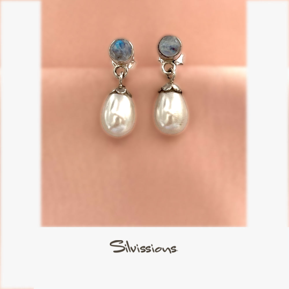 A pair of sterling silver stud earrings featuring a rainbow moonstone gemstone set above a faux pearl, displayed against a pink background with the text 'Rainbow Moonstone' and 'Silvissions'.