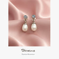 Faux pearl earrings with rainbow moonstone stones on a pink satin background, featuring the brand 'Silvissions'.