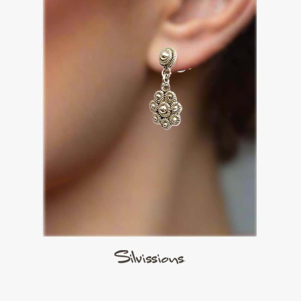 Decorative silver earring worn on an ear with 'Silvissions' branding.