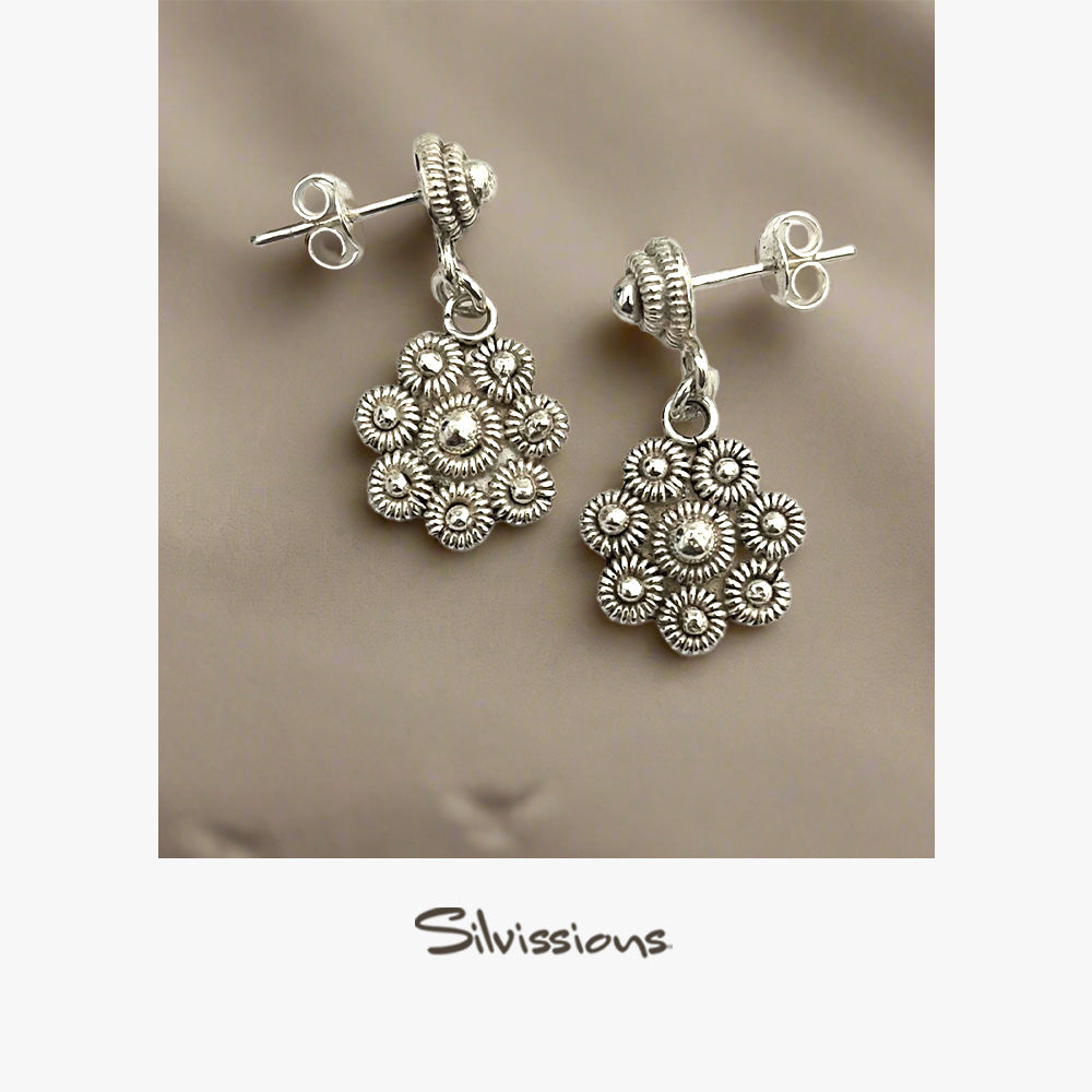 Silver floral earrings on a beige background with 'Silvissions' branding.