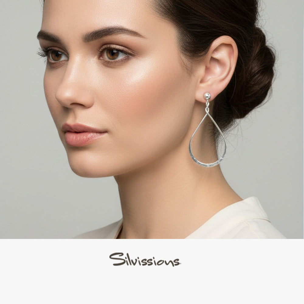 Woman wearing a silver earring with 'Silvissions' branding on a gray background
