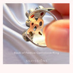 Festive gemstones ring held by a hand with 'Silvissions' branding.